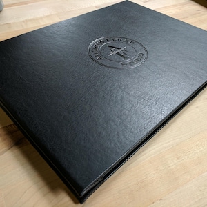 May include: A black leather-bound portfolio with a debossed logo that reads "Andrew Feiler Studio" in a circle.