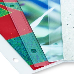 May include: A set of clear plastic sheet protectors with holes punched in the top corners. The sheet protectors are layered on top of each other, with a red, green, and blue patterned sheet underneath.