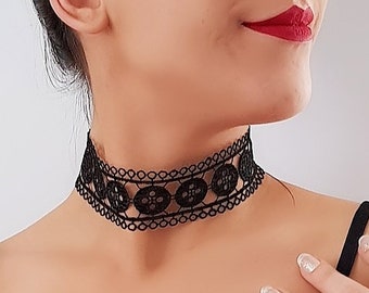 May include: A black lace choker necklace with a delicate floral pattern. The necklace is worn by a person with red lipstick and a black off-the-shoulder top.