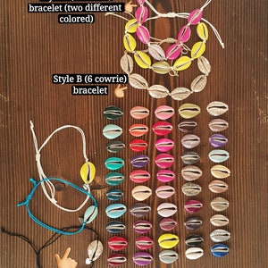 May include: Three styles of cowrie shell bracelets. The top bracelet has seven shells in two colors, yellow and pink. The middle bracelet has six silver cowrie shells. The bottom bracelet has one blue cowrie shell. All bracelets are on white string.