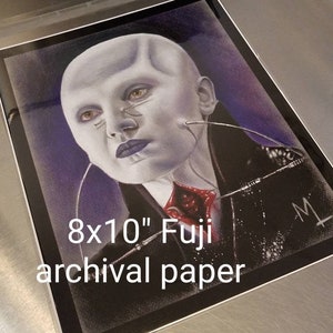 May include: A black and white drawing of a woman with a pale face and a red and black outfit. The drawing is on 8x10 inch Fuji archival paper.