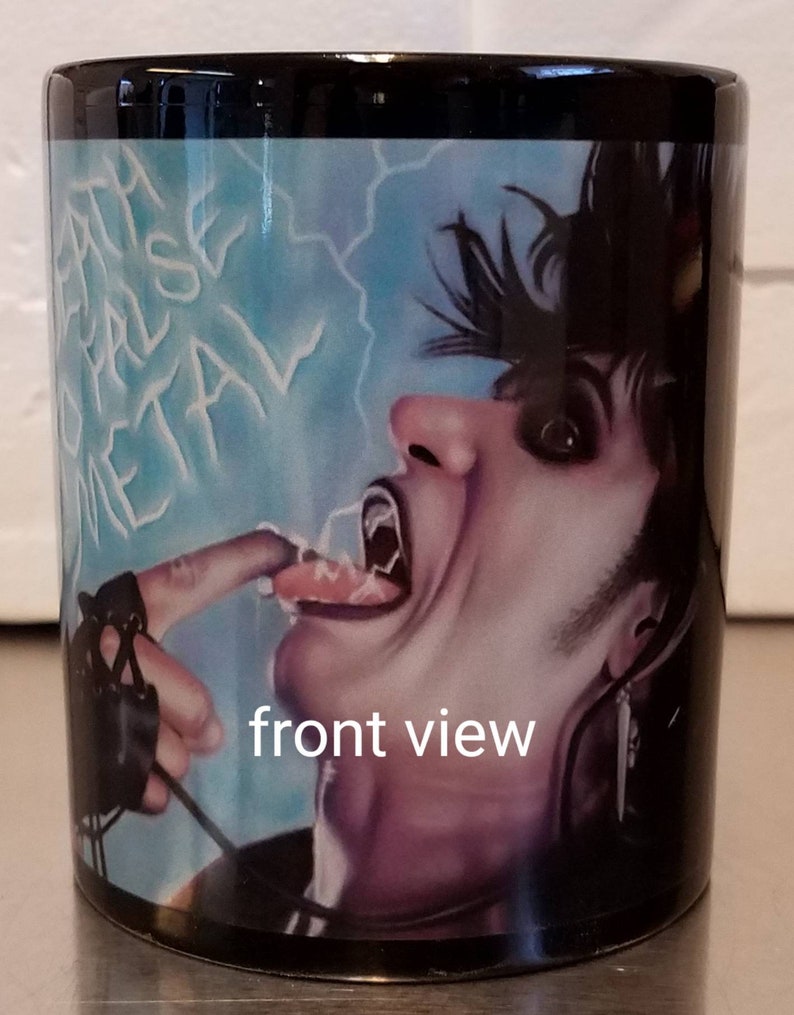 May include: Black coffee mug with a colorful image of a person with black hair and a black leather glove. The person is sticking their tongue out and the image has the words "Death Metal" written in white on a blue background.