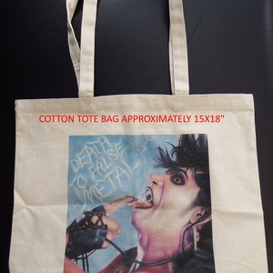 May include: A white cotton tote bag with a graphic print of a person with long black hair and a black leather glove. The graphic is of a person with their tongue sticking out and the text "Death to False Metal" is visible. The bag is approximately 15x18 inches.