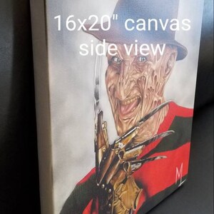 May include: A 16x20 inch canvas painting of Freddy Krueger from the Nightmare on Elm Street movie franchise. He is wearing a red and green striped sweater, a brown fedora hat, and a glove with razor-sharp blades. He has a menacing smile and is looking directly at the viewer.