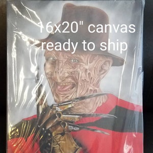 May include: A 16x20 inch canvas print of Freddy Krueger from the Nightmare on Elm Street movie franchise. He is wearing a red and black striped sweater and a brown fedora. He has a menacing expression on his face and is holding a glove with razor-sharp blades.