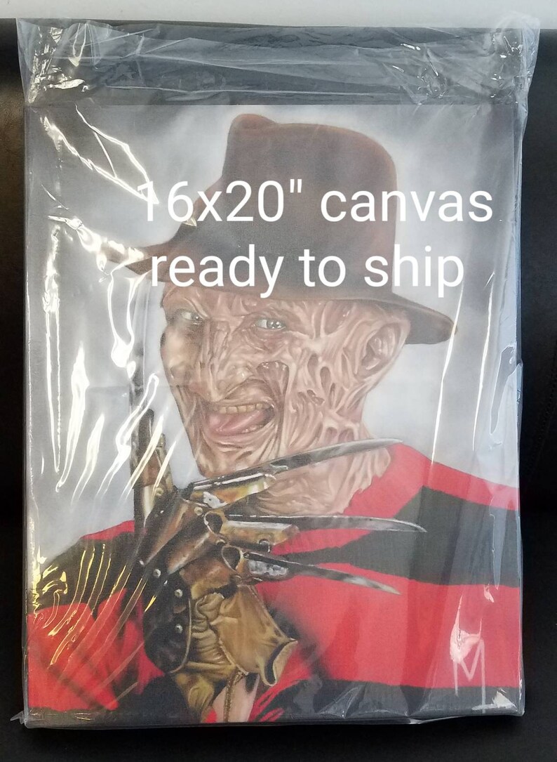 May include: A 16x20 inch canvas print of Freddy Krueger from the Nightmare on Elm Street movie franchise. He is wearing a red and black striped sweater and a brown fedora. He has a menacing expression on his face and is holding a glove with razor-sharp blades.