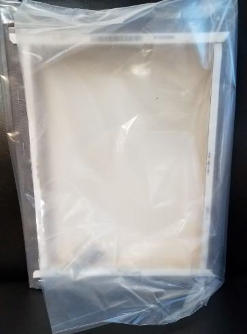 May include: A clear plastic bag with a white frame inside. The bag is folded over the frame, and the frame is visible through the plastic.