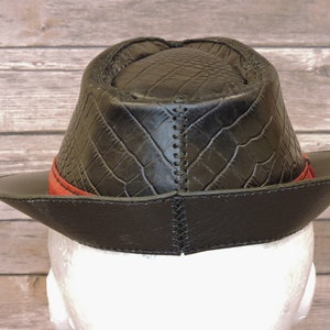 K&ouml;nnte beinhalten: Schwarzer Lederhut im Fedora-Stil mit rotem Band und Kroko-Pr&auml;gung.