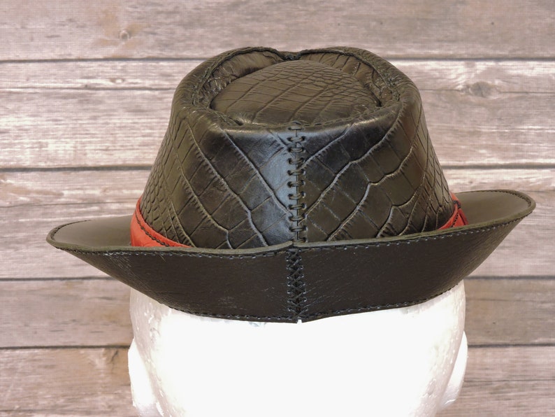 K&ouml;nnte beinhalten: Schwarzer Lederhut im Fedora-Stil mit rotem Band und Kroko-Pr&auml;gung.