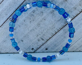 May include: A blue and white beaded bracelet with a silver clasp. The bracelet is made with round and square beads.