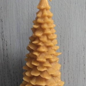 Puede incluir: Una vela de árbol de Navidad de cera de abejas amarilla alta con un diseño texturizado y en capas.
