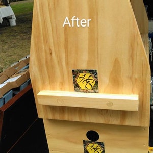 K&ouml;nnte beinhalten: Eine helle Bienenstockstruktur aus Holz mit dem in Wei&szlig; gedruckten Wort After. Sie enth&auml;lt zwei schwarze, kreisf&ouml;rmige Bel&uuml;ftungs&ouml;ffnungen und zwei quadratische Aufkleber mit gelbem Wabenmuster und den schwarzen Buchstaben HB auf der Vorderseite.