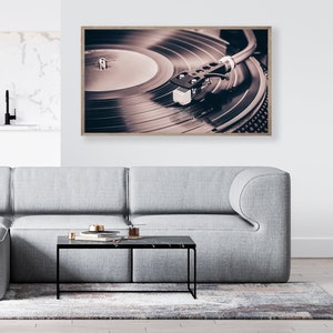 Peut inclure: Une photographie encadr&eacute;e d'un tourne-disque vintage avec un disque vinyle noir tournant sur le plateau. L'aiguille est dans le sillon du disque et le bras de lecture est &eacute;tendu. L'image est en s&eacute;pia.