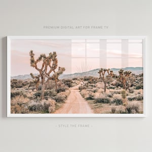 May include: A framed landscape print featuring a desert scene with Joshua trees, a dirt road, and mountains under a soft pink and peach sky. The text "PREMIUM DIGITAL ART FOR FRAME TV" and "- STYLE THE FRAME -" are visible.