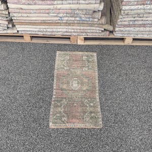 May include: A rectangular area rug featuring a central medallion design in muted shades of dusty rose, sage green, and cream. The rug displays a symmetrical pattern with geometric borders and intricate floral motifs woven throughout the fabric surface.