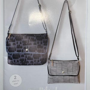 Può includere: Un modello per una borsa a tracolla compatta, intitolato "TRAVERSE BAG". La copertina presenta due modelli di borse: uno con un motivo a paesaggio urbano grigio e un altro con strisce orizzontali. Il testo indica che il modello include due taglie da cucire.