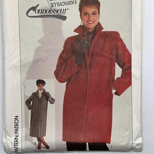 May include: A Simplicity sewing pattern envelope, number 7748, size 14. The front features a photograph of a long, red coat with a high collar and a smaller inset image of a long, grey, textured coat. The text includes Simplicity and Connoisseur.