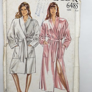May include: A New Look 6485 sewing pattern envelope for a robe in sizes 8-20. The illustration shows two variations of a long-sleeved robe with a shawl collar, a tie belt, and two front patch pockets. One robe is depicted in grey and the other in pink.