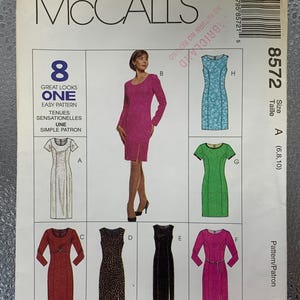May include: McCall's sewing pattern featuring eight dress designs. The pattern includes various styles, from a long-sleeved magenta dress to a sleeveless black dress. The pattern size is A (6,8,10). The text on the pattern reads "GREAT LOOKS ONE EASY PATTERN".