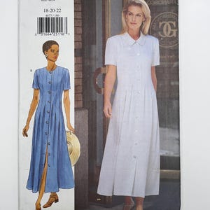May include: Butterick sewing pattern 4877 for a button-front dress with short sleeves and a collar. The envelope displays two variations of the dress, one in blue and one in white, with size range 18-20-22 and a barcode printed on the front.