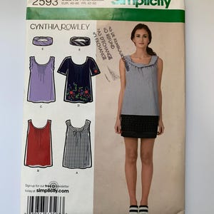 May include: A sewing pattern for a women's top with different neckline and sleeve options. The pattern is from Simplicity and is designed by Cynthia Rowley. The pattern number is 2593 and the sizes are R5, 14, 16, 18, 20, and 22. The pattern includes instructions for making a sleeveless top with a ruffled neckline, a short-sleeved top with a ruffled neckline, a sleeveless top with a scoop neckline, and a sleeveless top with a scoop neckline and stripes.