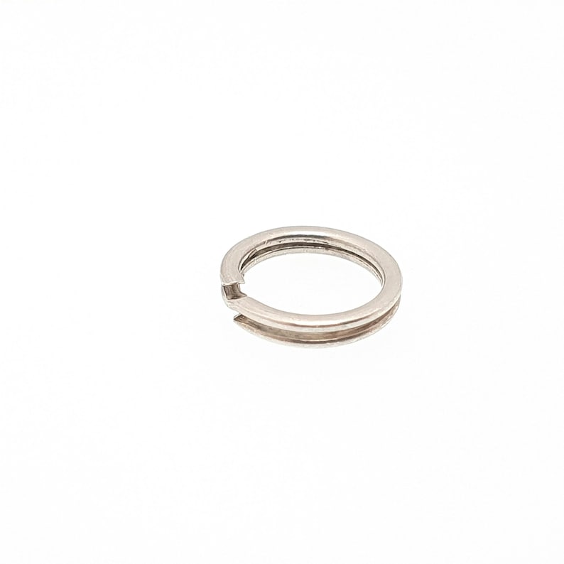 May include: A silver split ring, featuring a double-layered design. The ring is open at one point, allowing for the attachment of keys or other small items. The split ring is shown against a white background.