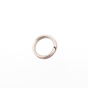 May include: A small, silver-coloured split ring, designed to hold keys or other small items. The ring is circular with a split, allowing items to be added or removed. The metal has a slightly worn appearance, suggesting it is made of a durable material.