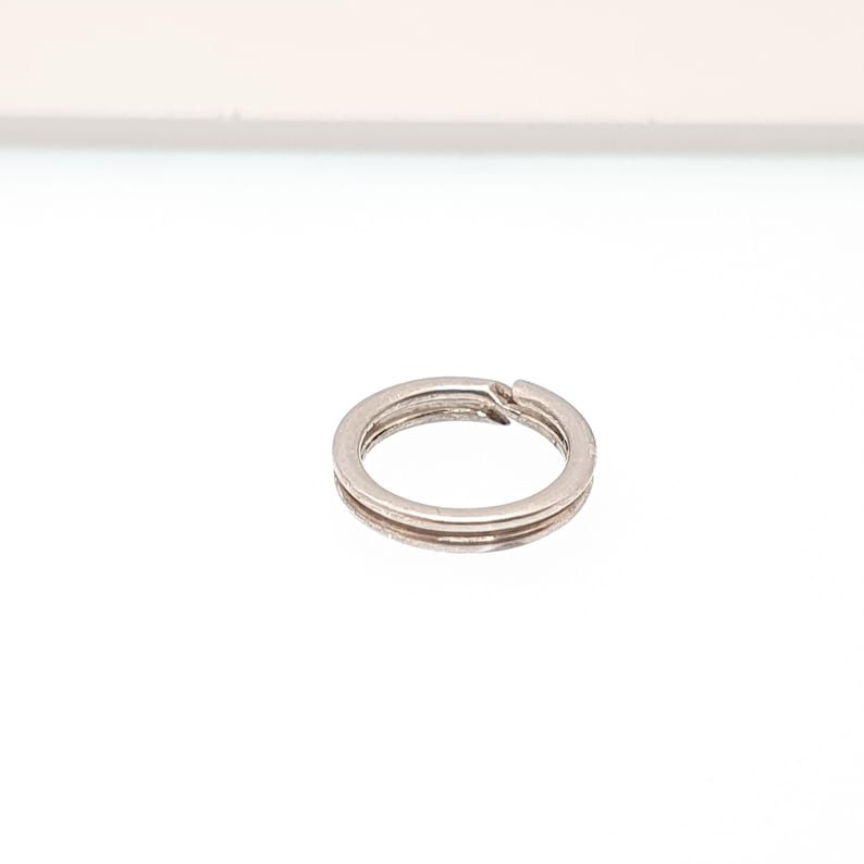 May include: A small, silver split key ring. The key ring is circular with a split for adding keys. The key ring is made of metal and has a shiny finish. A common item for organizing keys.