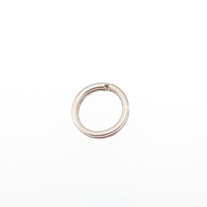 May include: A silver split ring, a small metal ring with a split, used for attaching keys or other items. The ring is circular and has a double-loop design. The background is plain white.