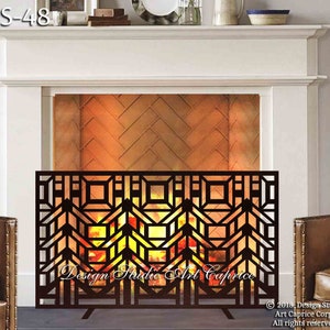 Peut inclure: Un pare-feu en métal noir avec un motif géométrique. L'écran est devant une cheminée avec un entourage en brique et un feu qui brûle à l'intérieur. L'écran est étiqueté "Design Studio Art Caprice".