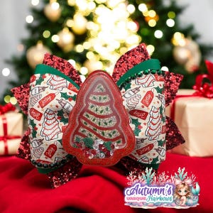 May include: A festive Christmas hair bow featuring a red sequined bow base, green accents, and a central red tree-shaped shaker element filled with glitter. The bow has a printed pattern with Christmas trees and the word "Jolly".