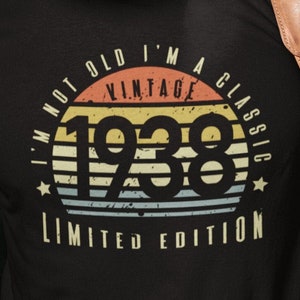 Puede incluir: Una camiseta negra con un gráfico de estilo vintage que dice "I'm not old I'm a vintage classic 1938 limited edition". El gráfico presenta una puesta de sol con una estrella a cada lado.