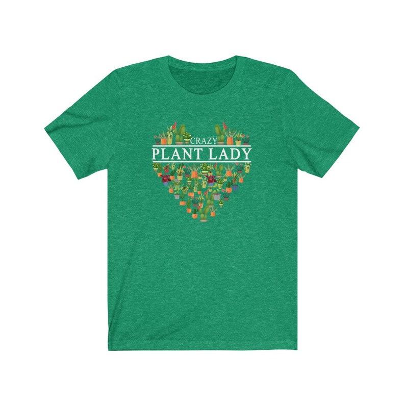 Puede incluir: Camiseta verde de manga corta con un dise&ntilde;o blanco en forma de coraz&oacute;n con el texto "Crazy Plant Lady" y una variedad de plantas en macetas.