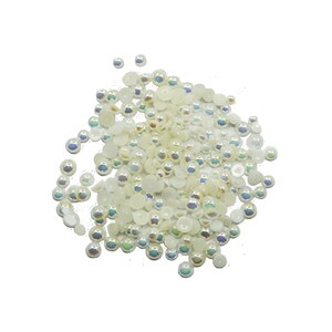 May include: A large pile of white iridescent pearl beads. The beads are various sizes and shapes, with some being round and others being flat.