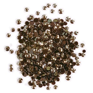 May include: A large pile of dark brown rhinestones, scattered on a white background. The rhinestones are various sizes and shapes, with some having a more faceted appearance.