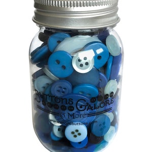 May include: A glass jar filled with blue and white buttons. The jar has a silver lid and a label that reads "Buttons Galore & More" with the website address "www.morebuttons.com".