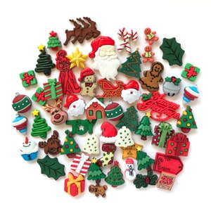May include: A collection of Christmas-themed embellishments, including Santa Claus, reindeer, Christmas trees, gift boxes, gingerbread men, and holly leaves. The embellishments are in various colors, such as red, green, white, and brown. Some have the text "Joy" and "Merry Christmas".