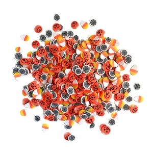 Op de afbeelding: Een grote stapel oranje, witte en zwarte Halloween-sprinkels. De sprinkels zijn gevormd als pompoenen, snoepmais en spinnenwebben.