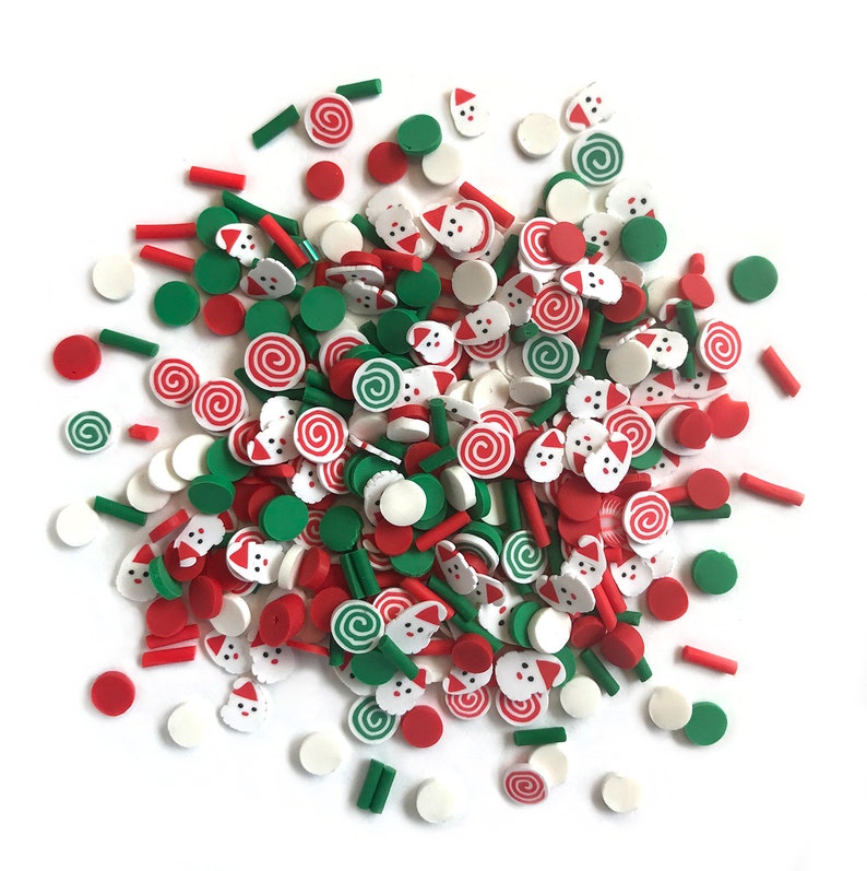 Op de afbeelding: Een grote verzameling kleurrijke kerstthema polymer clay sprinkles. De sprinkles zijn in de vorm van snoepstokken, kerstmangezichten en kleine cirkels in rood, groen en wit.