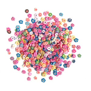 Op de afbeelding: Een grote verzameling kleurrijke, kleine, plastic bloemencharms. De charms zijn in verschillende tinten roze, blauw, geel, groen en wit.