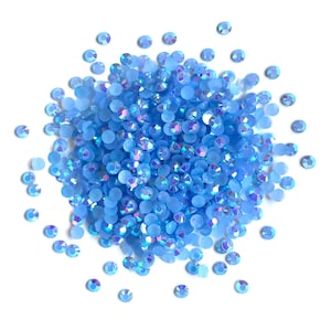 May include: A large pile of light blue iridescent rhinestones, with a few scattered around the pile.