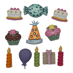 May include: A collection of colorful, ceramic birthday-themed embellishments. The set includes two cakes, two cupcakes, a party hat, a balloon, two candles, a wrapped gift, and a candy. The items are in shades of pink, yellow, green, orange, and purple.