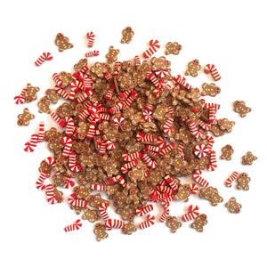 Op de afbeelding: Een grote stapel peperkoekmannetjes en snoepstokken. De peperkoekmannetjes zijn bruin met witte glazuur en zwarte ogen. De snoepstokken zijn rood en wit.