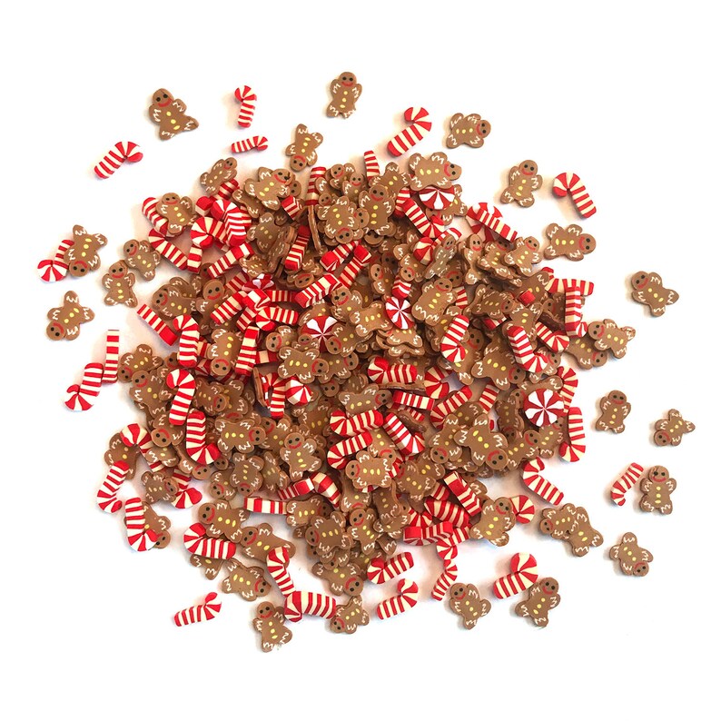 Op de afbeelding: Een grote stapel peperkoekmannetjes en snoepstokken. De peperkoekmannetjes zijn bruin met witte glazuur en zwarte ogen. De snoepstokken zijn rood en wit.