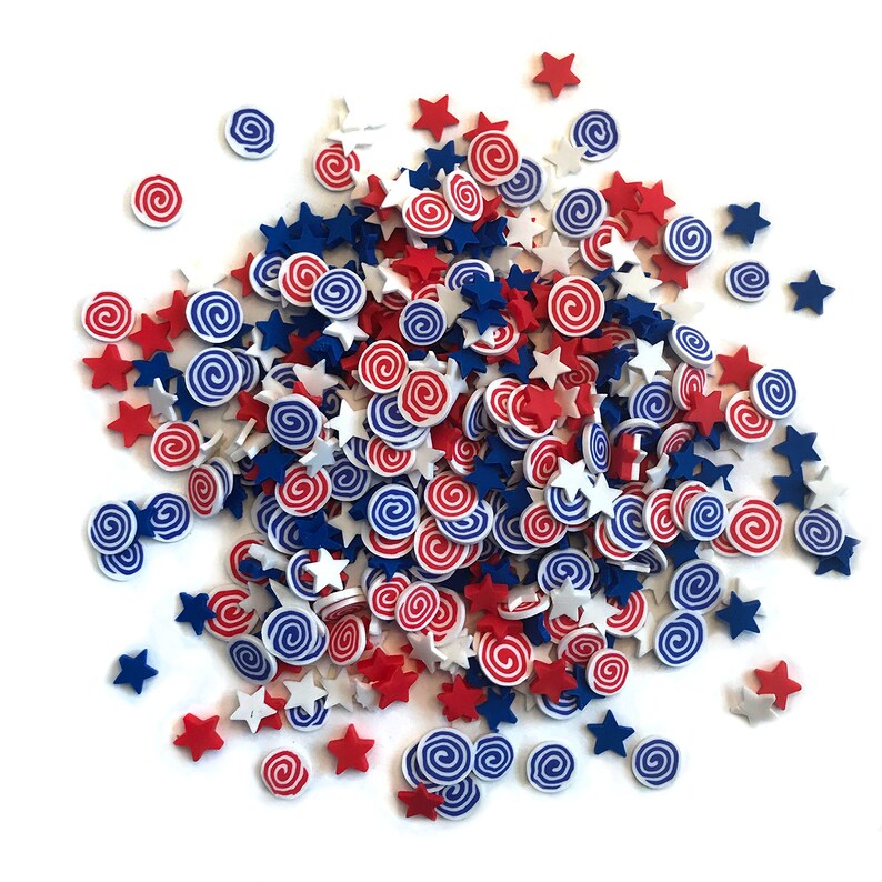 Op de afbeelding: Een hoop rode, witte en blauwe sprinkles in de vorm van sterren en swirls.