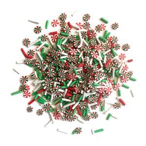 Op de afbeelding: Een hoop rode, witte en groene snoepjes. De snoepjes zijn in de vorm van snoepstokken en kleine stokjes.