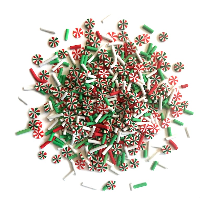 Op de afbeelding: Een hoop rode, witte en groene snoepjes. De snoepjes zijn in de vorm van snoepstokken en kleine stokjes.
