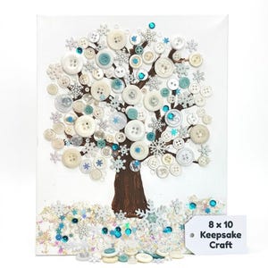 May include: An 8 x 10 inch canvas art piece featuring a tree design made from various white, cream, and blue buttons and snowflake embellishments. The tree trunk is painted brown, and the base has scattered sequins and buttons. The text "Keepsake Craft" is included.