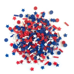 Op de afbeelding: Een verzameling rode, witte en blauwe sprinkles in de vorm van sterren en cirkels. De sprinkles zijn perfect om taarten, cupcakes en andere desserts te versieren.