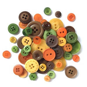 May include: Assortment of colorful buttons in various sizes and shapes, including brown, green, orange, and yellow. The buttons are made of plastic and have a smooth finish.